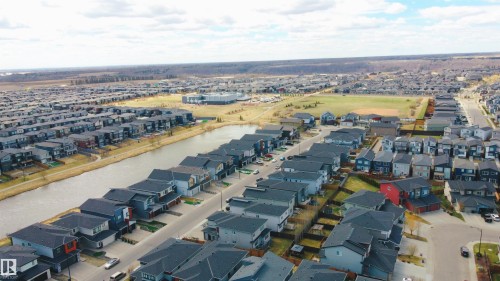Aerial perspective showcasing a residential community with a central water feature, an expansive green space, and a mix of modern architectural styles - 2704 Koshal Place, Edmonton, AB - Outdoor With View