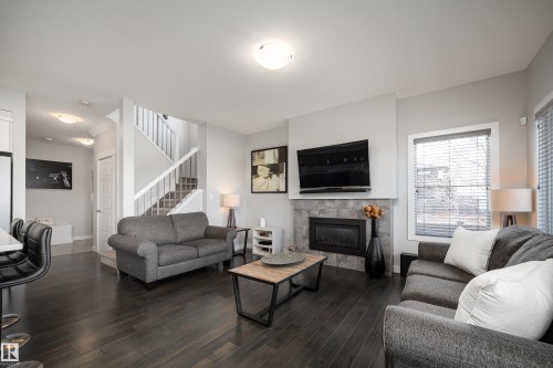 Living area with dark wood-finish flooring, a tile-surround fireplace, and a window with blinds - 2704 Koshal Place, Edmonton, AB - Indoor Photo Showing Living Room With Fireplace