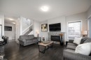 Living area with dark wood-finish flooring, a tile-surround fireplace, and a window with blinds - 2704 Koshal Place, Edmonton, AB  - Indoor Photo Showing Living Room With Fireplace 