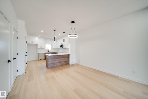 Spacious open-concept area featuring light wood-finish flooring, white walls, and recessed lighting - 86 Blackbird Bend, Fort Saskatchewan, AB - Indoor