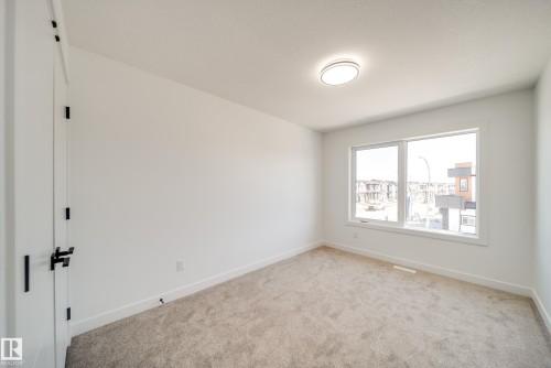 Bright room with neutral carpet flooring, a large multi-pane window, white walls, and a contemporary flush-mount ceiling light fixture - 86 Blackbird Bend, Fort Saskatchewan, AB - Indoor Photo Showing Other Room