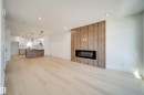 Open concept living area featuring light wood-finish flooring, recessed lighting, and a linear electric fireplace with a wood-look accent wall - 86 Blackbird Bend, Fort Saskatchewan, AB  - Indoor Photo Showing Living Room With Fireplace 
