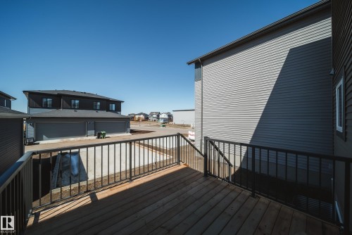 Expansive wood-finish decking featuring black metal railings and exterior stairs - 86 Blackbird Bend, Fort Saskatchewan, AB - Outdoor With Exterior
