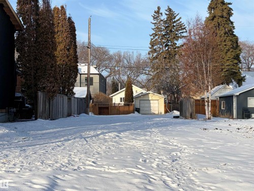 The property features a spacious lot with a snow-covered ground and a wooden fence along the perimeter - 11138 65 Street Nw, Edmonton, AB 
