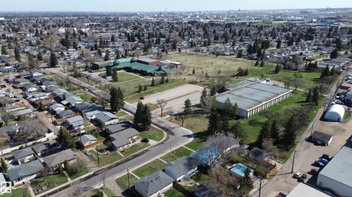Aerial view of a residential neighborhood with detached homes, mature trees, green spaces, and a commercial-style building - 6832 83 Avenue, Edmonton, AB - Outdoor With View
