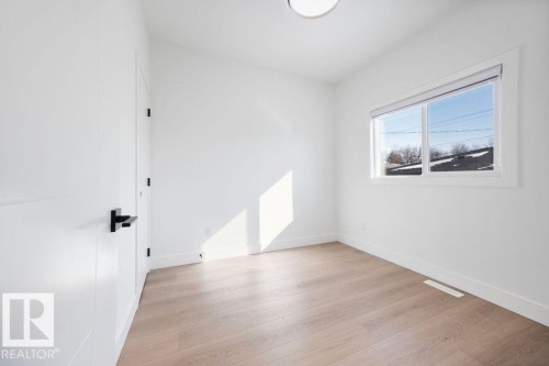 This bright room features light-toned flooring, white walls, and a window providing natural light and views of the outdoors - 12307 91 St Nw, Edmonton, AB - Indoor Photo Showing Other Room