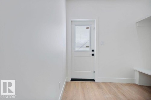 Entryway featuring light hardwood floors, white walls, and a white door with a window and black hardware - 12307 91 St Nw, Edmonton, AB - Indoor Photo Showing Other Room