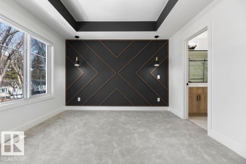 The room features a stylish accent wall with geometric wood trim, two pendant light fixtures, and a tray ceiling with a dark accent - 12307 91 St Nw, Edmonton, AB - Indoor Photo Showing Other Room