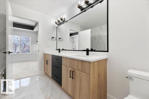 This bathroom features a double vanity with light wood and dark drawer cabinetry, white countertops, and dual black faucets - 12307 91 St Nw, Edmonton, AB - Indoor Photo Showing Bathroom