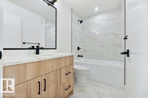 Well-appointed bathroom featuring a wooden vanity with a white countertop and a black-framed mirror - 12307 91 St Nw, Edmonton, AB - Indoor Photo Showing Bathroom