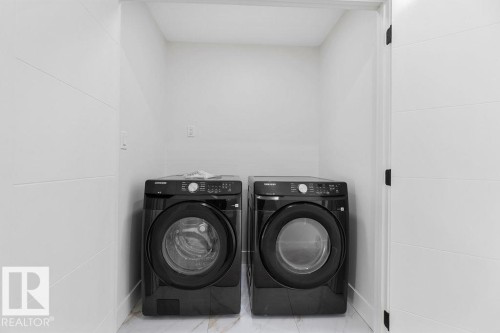 Dedicated laundry area featuring a front-loading washer and dryer set, white walls, and a tiled floor - 12307 91 St Nw, Edmonton, AB - Indoor Photo Showing Laundry Room