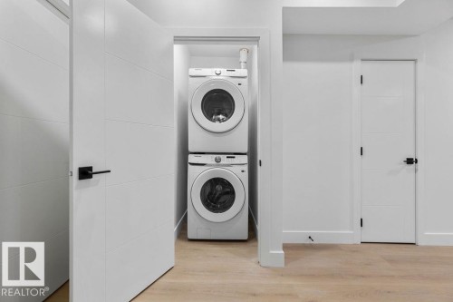 Convenient laundry area featuring a stacked washer and dryer, complemented by light-toned flooring - 12307 91 St Nw, Edmonton, AB - Indoor Photo Showing Laundry Room