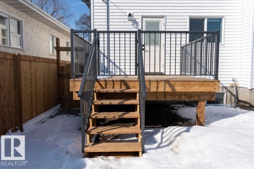 The property features a wooden deck with black metal railings and a wooden staircase - 12307 91 St Nw, Edmonton, AB - Outdoor With Exterior