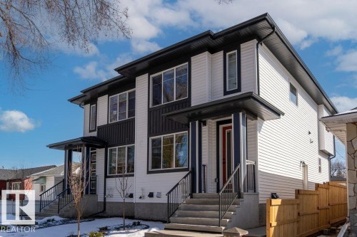 The property features a contemporary exterior with white siding and dark accents, multiple windows, and a red front door - 12307 91 St Nw, Edmonton, AB - Outdoor