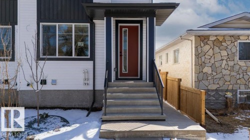 The property features a bold red entry door with a vertical window, complemented by a covered porch area - 12307 91 St Nw, Edmonton, AB - Outdoor