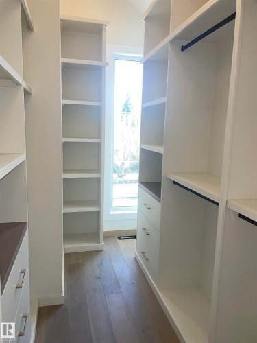 Custom-built closet system featuring wood-finish flooring, white cabinetry, built-in shelving, drawers with brushed nickel hardware, and hanging rods - 14344 92A Avenue, Edmonton, AB - Indoor With Storage