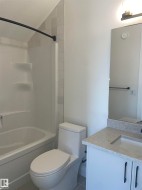 Bathroom featuring a white vanity with black hardware, a light-toned countertop, and a rectangular undermount sink - 