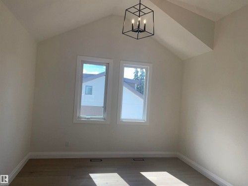 Upper-level landing featuring light wood-finish flooring, a dark metal balustrade, and a contemporary chandelier - 14344 92A Avenue, Edmonton, AB - Indoor Photo Showing Other Room