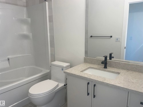 Spacious room featuring light wood-finish flooring, white baseboards, and a large three-panel window with white trim - 14344 92A Avenue, Edmonton, AB - Indoor Photo Showing Other Room