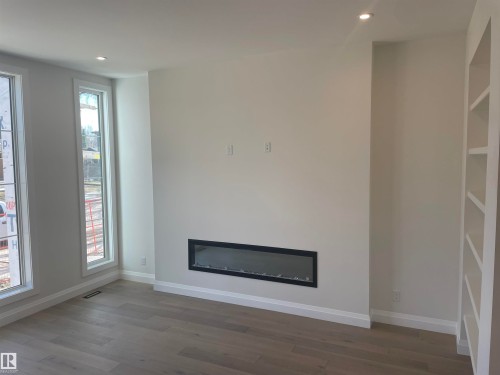 Entryway featuring a decorative built-in shelving unit, hardwood flooring, and a modern staircase with dark iron balusters - 14344 92A Avenue, Edmonton, AB - Indoor Photo Showing Other Room