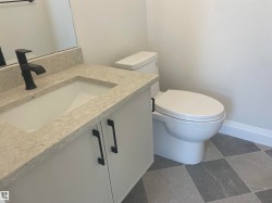 Bathroom vanity featuring a light-toned countertop, integrated sink, and white cabinetry with matte black hardware - 