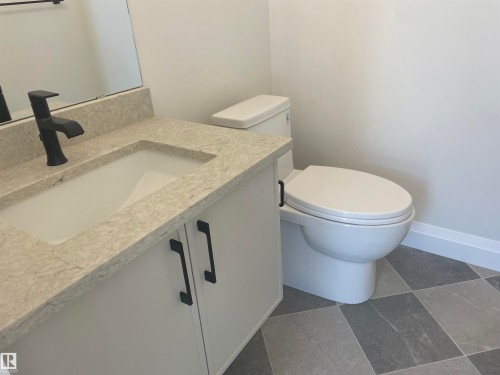 Bathroom vanity featuring a light-toned countertop, integrated sink, and white cabinetry with matte black hardware - 14344 92A Avenue, Edmonton, AB - Indoor Photo Showing Bathroom