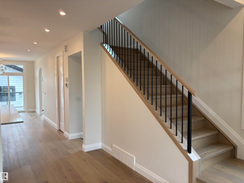 Entryway mudroom featuring built-in cabinetry, a wood-finish bench with cubby storage, three wall-mounted hooks, and a full-light exterior door with black hardware - 14344 92A Avenue, Edmonton, AB - Indoor Photo Showing Other Room