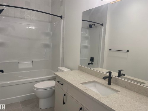 Bathroom featuring a full vanity with a light-toned countertop, an integrated sink, and matte black fixtures - 14344 92A Avenue, Edmonton, AB - Indoor Photo Showing Bathroom