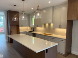 Modern kitchen featuring a large central island with a light-colored countertop - 