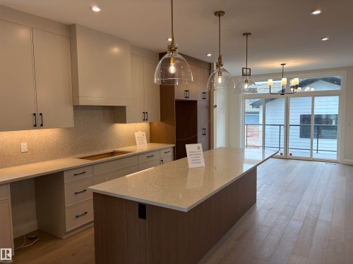 Contemporary kitchen featuring two-tone cabinetry, light-toned countertops, and a central island - 14344 92A Avenue, Edmonton, AB - Indoor Photo Showing Kitchen