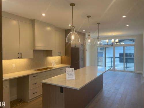 Contemporary kitchen featuring light-toned cabinetry, a large center island with a light countertop, and integrated under-cabinet lighting - 14344 92A Avenue, Edmonton, AB - Indoor Photo Showing Kitchen
