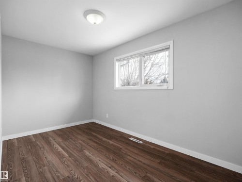 Room featuring wood-finish flooring, light gray walls, a flush-mount ceiling light, and a white-framed window with blinds - 8703 73 Street, Edmonton, AB - Indoor Photo Showing Other Room