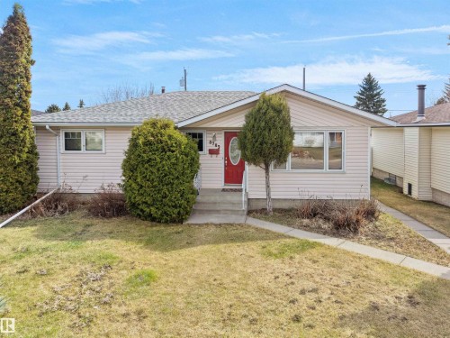 Single-story residence featuring light-colored siding, a prominent red entry door with an oval window, multiple front-facing windows, and a concrete walkway - 8703 73 Street, Edmonton, AB - Outdoor