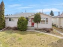 Single-story residence featuring light-colored siding, a prominent red entry door with an oval window, multiple front-facing windows, and a concrete walkway - 8703 73 Street, Edmonton, AB  - Outdoor 