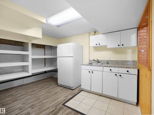 Kitchenette featuring white cabinetry, a stainless steel sink, and a speckled countertop - 8703 73 Street, Edmonton, AB - Indoor Photo Showing Kitchen