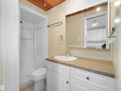 Bathroom featuring a white integrated shower, toilet, and a vanity with a white basin and a speckled countertop - 8703 73 Street, Edmonton, AB - Indoor Photo Showing Bathroom