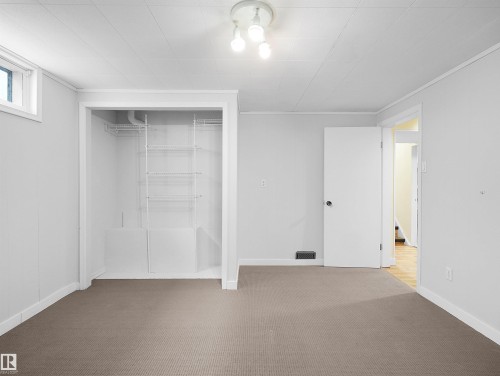 Carpeted room featuring a built-in closet with wire shelving, white paneled walls, and a recessed window - 8703 73 Street, Edmonton, AB - Indoor Photo Showing Other Room
