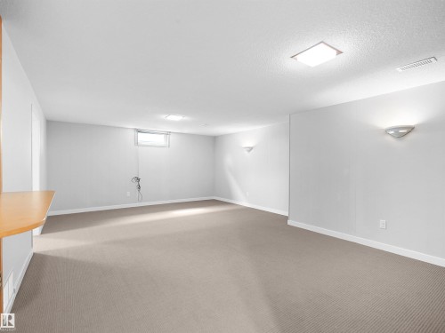 Spacious room featuring neutral carpeting, light-toned walls, a rectangular window, and a built-in wood-finish shelf - 8703 73 Street, Edmonton, AB - Indoor