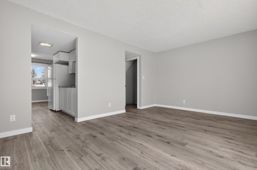 Living area featuring wood-finish flooring, light gray wall paint, and white baseboards - 18 Lakewood Village, Edmonton, AB - Indoor Photo Showing Other Room