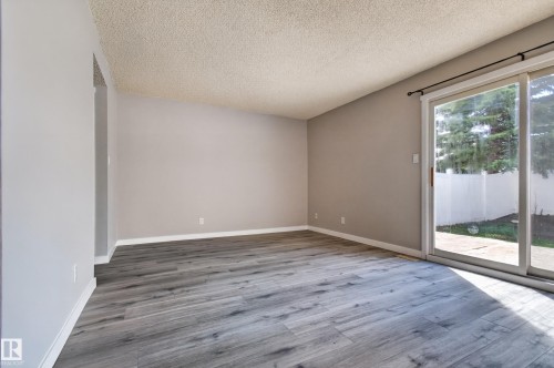 Spacious interior featuring wood-finish flooring, neutral wall tones, and a sliding glass door providing exterior access - 18 Lakewood Village, Edmonton, AB - Indoor Photo Showing Other Room
