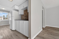Kitchenette area featuring white cabinetry, a dark countertop, and a dark-toned backsplash - 