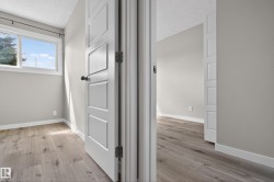 Interior room with wood-finish flooring, light grey painted walls, and white baseboards - 