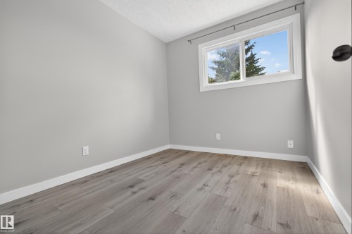 Spacious room featuring light gray wall paint, white trim, and wood-finish flooring - 18 Lakewood Village, Edmonton, AB - Indoor Photo Showing Other Room