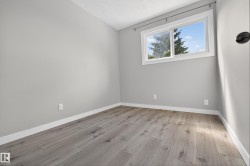 Spacious room featuring light gray wall paint, white trim, and wood-finish flooring - 