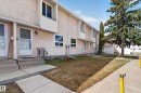 Multi-level stucco exterior featuring white-framed windows, a concrete walkway, and a landscaped front yard with a mature evergreen - 18 Lakewood Village, Edmonton, AB  - Outdoor 