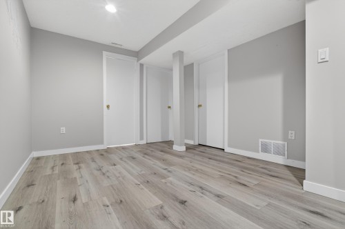 Spacious interior featuring wide plank wood-finish flooring, light gray wall paint, crisp white baseboards, and recessed ceiling lighting - 18 Lakewood Village, Edmonton, AB - Indoor Photo Showing Other Room