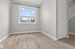 Bright room featuring a large window, wood-finish flooring, light grey wall paint, white baseboards, and a paneled bi-fold door - 