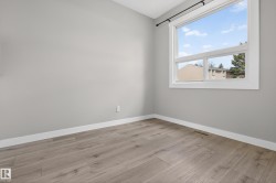 Room featuring light gray walls, white baseboards, and wood-finish flooring - 