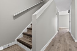 Open staircase featuring wood-finish treads and risers, white railing, and light gray wall paint - 