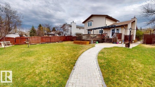 Expansive backyard featuring a winding paver walkway, a manicured lawn, and a wood privacy fence - 4116 55C Ave, Drayton Valley, AB - Outdoor With Deck Patio Veranda